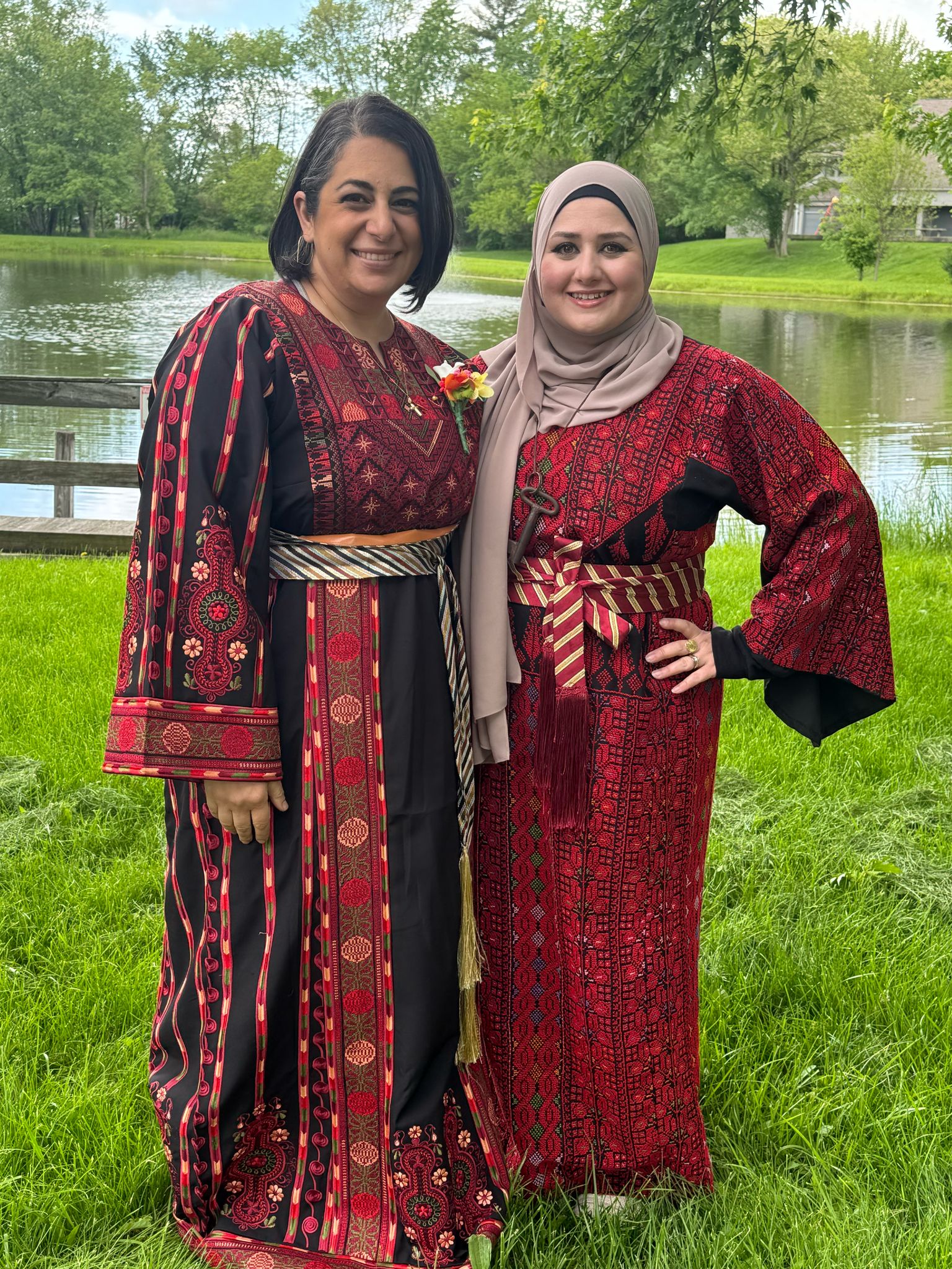Shereen Naser and a woman smile, each wearing a beautiful Palestinian trobe, or dress hand-stitched with embroidery